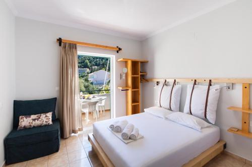 a bedroom with a bed and a chair and a window at Nikolas Studios in Agios Nikitas