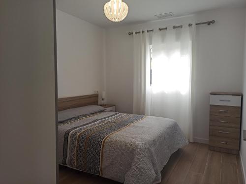 sypialnia z łóżkiem, komodą i oknem w obiekcie Casa cerca de la playa con patio y garaje privado w mieście Puerto de Sagunto