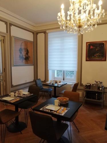 a dining room with tables and chairs and a chandelier at Chambres d'Hôtes de luxe Côté Parc-Côté Jardin avec parking privé gratuit in Nevers