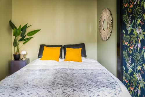a bedroom with a bed with two yellow pillows at La Palmeraie, rénové, central et proche plage in Dieppe