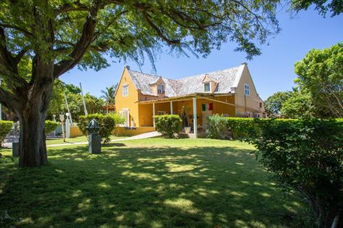 a yellow house with a tree in the yard at Blue Bay Apartments in Sint Michiel