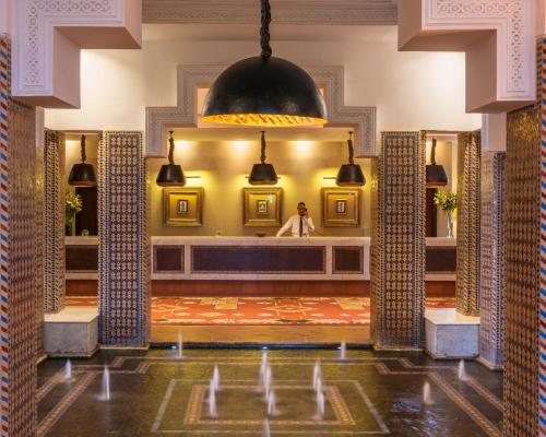 a woman standing in a bathroom in a mirror at Berbère Palace in Ouarzazate