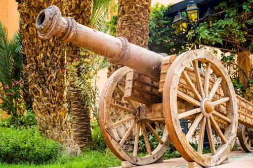 an old wooden cannon sitting next to a palm tree at Berbère Palace in Ouarzazate