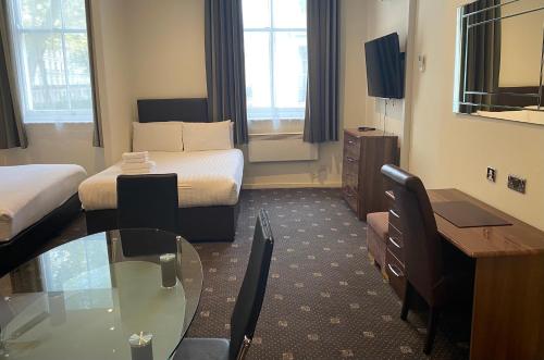 a hotel room with two beds and a glass table at Grand Plaza Serviced Apartments in London