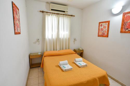 1 dormitorio con 1 cama con 2 toallas en Hotel Simón en Trenque Lauquen