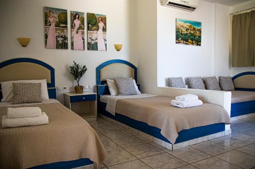 a bedroom with two beds and pictures on the wall at Castri Village Hotel in Palekastron