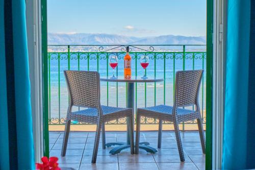 a table with two chairs and wine glasses on a balcony at Nikos Kalamaki Corfu in Apraos