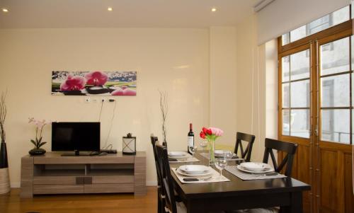 ein Esszimmer mit einem Tisch mit Stühlen und einem TV in der Unterkunft Apartments Porto Historico in Porto