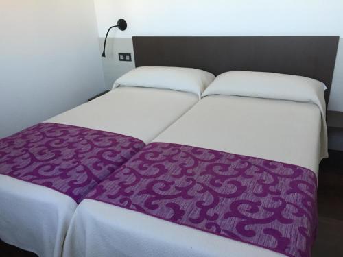 Una cama con una manta morada encima. en Hotel Rural En El Camino en Boadilla del Camino