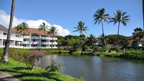 a river in front of a building with palm trees at Oceanview 1BR at Kiahuna Plantation Unit 170 in Koloa