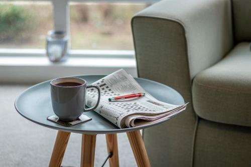 a cup of coffee and a newspaper on a glass table at Fishertown House in Nairn