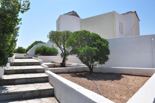 a white building with stairs and trees in front of it at Castri Village Hotel in Palekastron