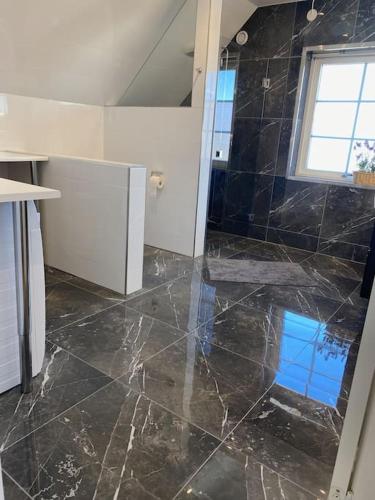 a bathroom with a black marble floor and a window at Rymlig och modern lägenhet i villa. Perfekt för familjer. Med parkering. in Malmö