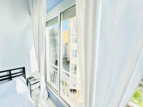 een slaapkamer met een groot raam met witte gordijnen bij Suite Casa del Sole 22 - Fronte mare in Sanremo