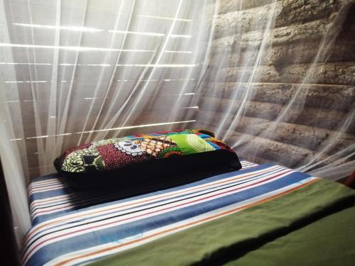 a pillow sitting on a bed in front of a curtain at Murchison Backpackers in Masindi
