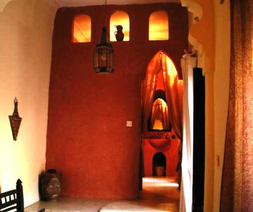 a hallway with a red wall with a lamp on it at Riad El Filali in Marrakesh