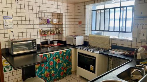 a kitchen with a stove and a microwave at Vila Santê in Belo Horizonte