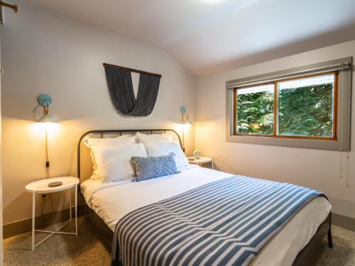 a bedroom with a bed with a blue and white striped blanket at Pendleton Pines Lodge in Glacier