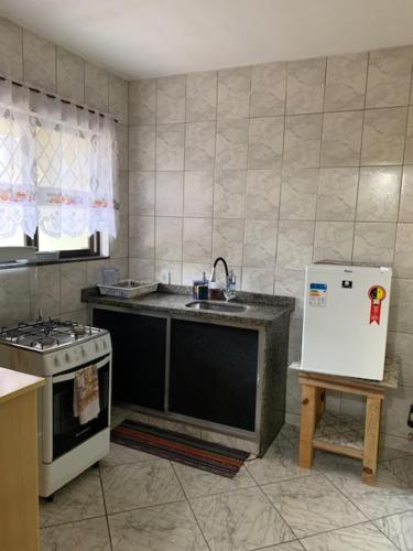 a kitchen with a sink and a stove and a refrigerator at Apartamento Vista da Montanha in Nova Friburgo