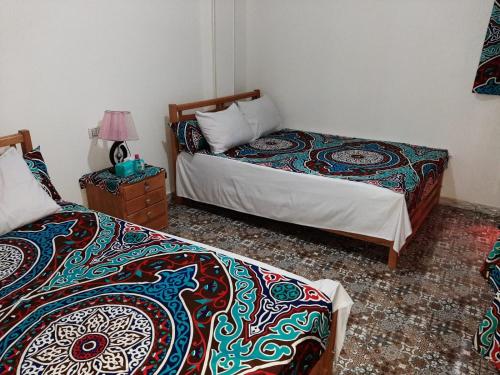 a bedroom with two beds and a table with a lamp at Ra Guest house in Cairo