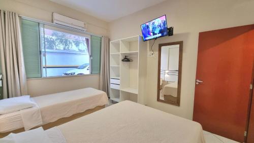 Habitación con 2 camas, espejo y TV. en Residencial Las Rocas I, en Florianópolis
