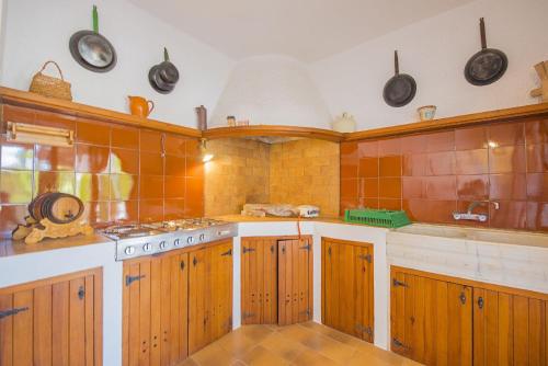 a kitchen with orange tiled walls and wooden cabinets at Villa Mas Blanc - PlusHolidays in Benissa