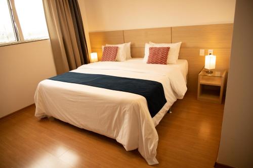 ein Schlafzimmer mit einem großen Bett mit weißer Bettwäsche und Kissen in der Unterkunft Hotel Franco in Dionísio Cerqueira