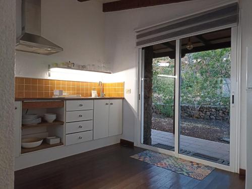 una cocina con armarios blancos y una puerta corredera de cristal en Dos Violetas, en Mocanal