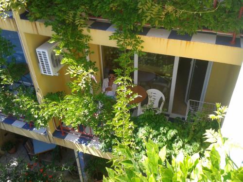 a person sitting on the balcony of a building with plants at The Colourful Mansion Hotel in Ahtopol
