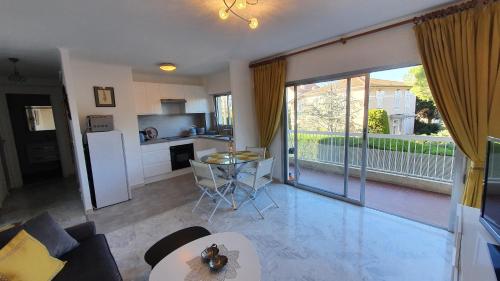 Il comprend un salon avec un canapé et une cuisine dotée d'une grande fenêtre. dans l'établissement Centre Cannes gd 2p terrasse parking 10mn palais plage, à Cannes