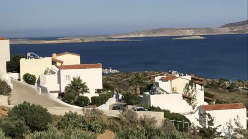a group of white buildings on a hill next to the water at Castri Village Hotel in Palekastron