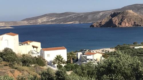 a group of white buildings on a hill next to the water at Castri Village Hotel in Palekastron