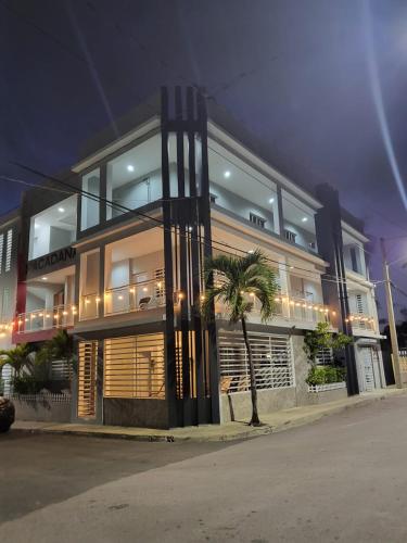 a building with a palm tree in front of it at Apartahotel MACADANA in Nagua
