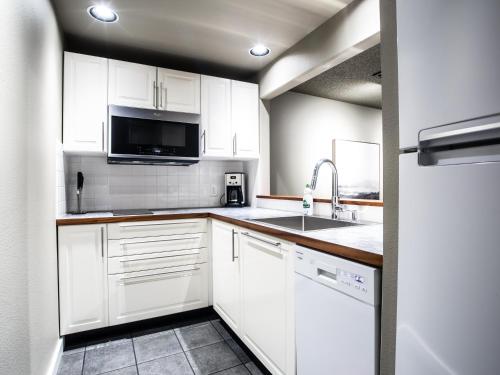 a white kitchen with a sink and a microwave at Snowater Respite in Deming