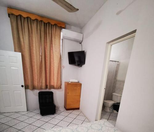 baño con aseo y TV en la pared en Hostal Tah Itza, en Flores