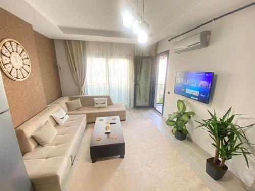 a living room with a couch and a clock on the wall at Merkezi konumda yeni dekore edilmiş şık daire in Mersin