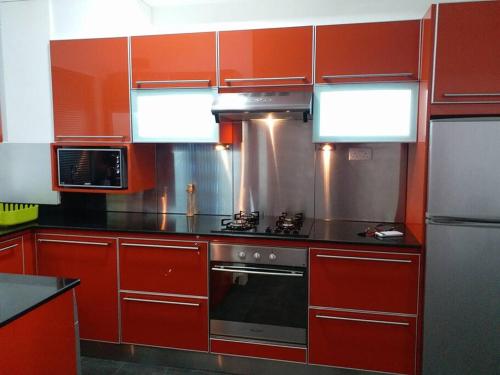 a kitchen with red cabinets and a stove top oven at Beachfront Apartment(roadside- 30 meters to beach) in Flic-en-Flac