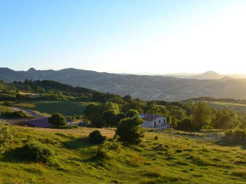 a house on a hill with mountains in the background at Fattoria Bio L'A Ceccoli in Sassofeltrio