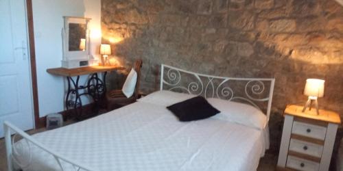 een slaapkamer met een wit bed en een stenen muur bij Charming 2-Bed Cottage within Barn in Merinchal in Mérinchal
