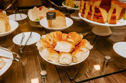 a table topped with plates of bread and pastries at Vitoria Praia Hotel in Vitória