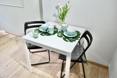 a white table with two chairs and a vase of flowers at Angel Apartment Taczaka in Poznań