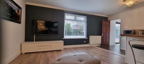 a living room with a tv on a wall at Laighdykes Guest Cottage in Saltcoats