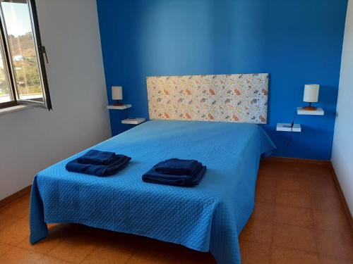 a blue bedroom with a bed with two towels on it at Casa dos Pais in Odeceixe