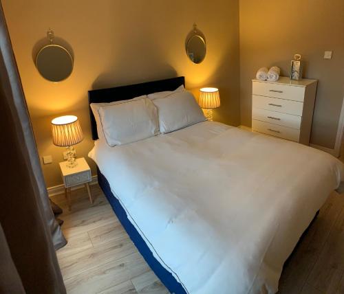 a bedroom with a large white bed with two lamps at Slane Stay, Belfast in Belfast