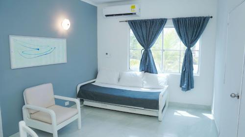 a bedroom with a bed and a chair and a window at MAKARY BEACH HOTEL in Tolú