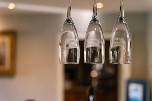 four wine glasses hanging from a chandelier at The Juniperlea Inn in Pathhead