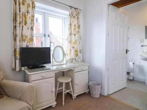 1 dormitorio con escritorio, TV y ventana en Old Barn, en Lichfield