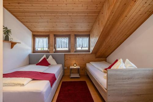 two beds in a small room with wooden ceilings at Gästehaus Nassfeld in Tröpolach