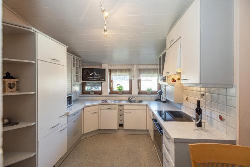 a large kitchen with white cabinets and a sink at Gästehaus Nassfeld in Tröpolach