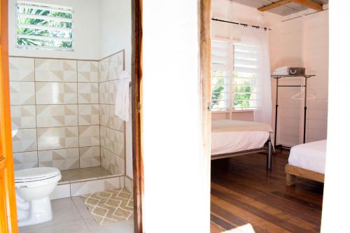 a bathroom with a toilet and a bedroom at Horse Cottage in Sarteneja
